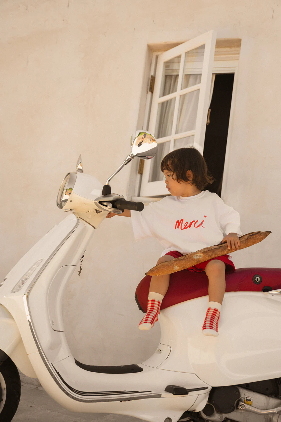 toddler in a printed white t-shirt, red shorts and gingham socks